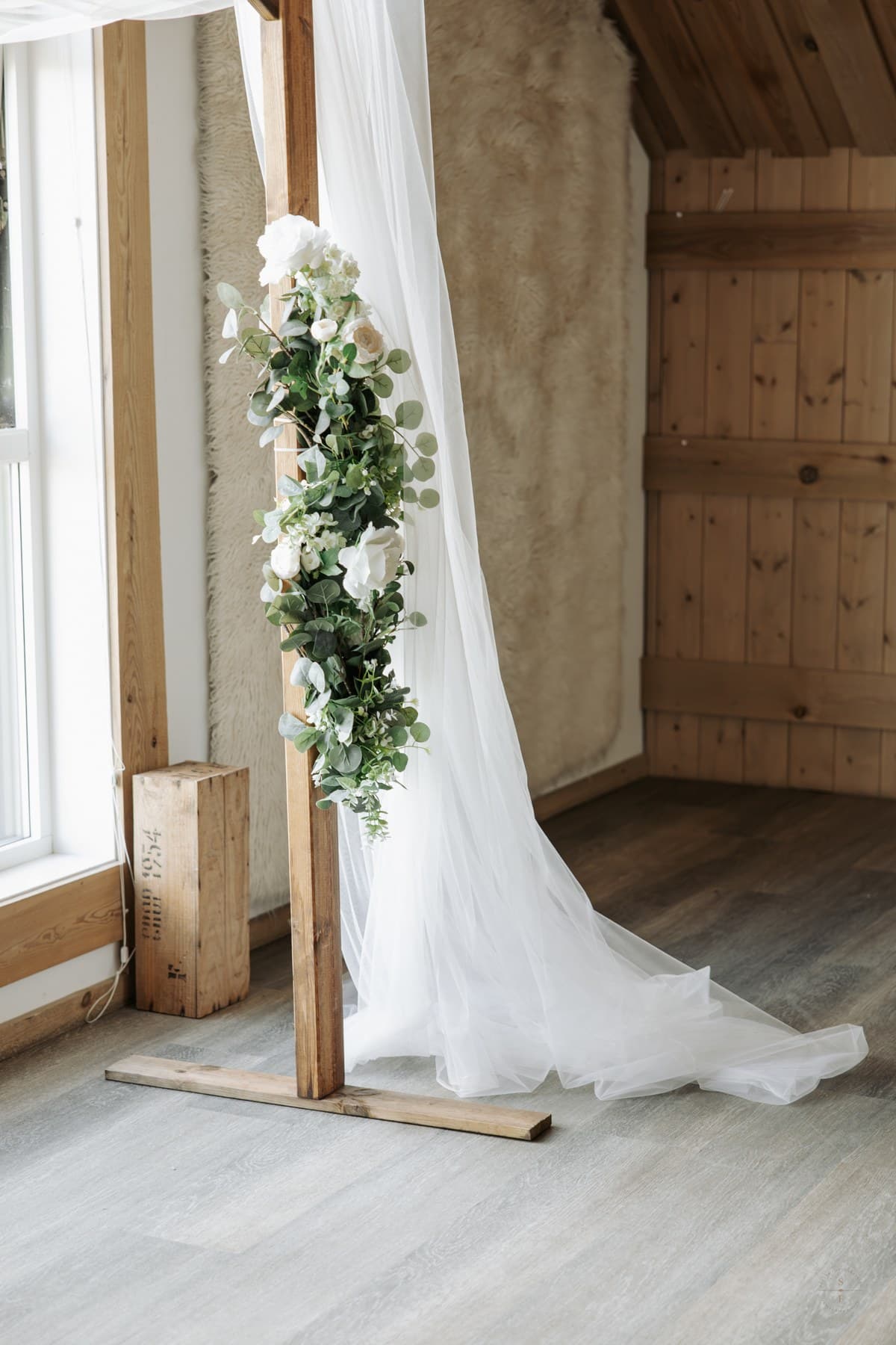 Vielsesdekor med hvite tekstiler og blomster i et lyst lokale